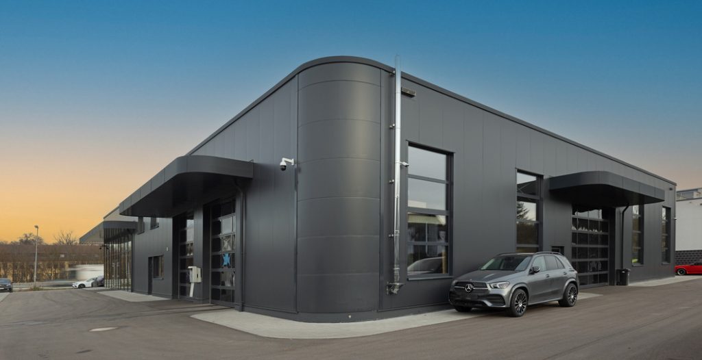 Moderne KFZ-Halle mit schwarzer Fassade und Mercedes SUV – Automobilhalle planen mit Hallenkonfigurator